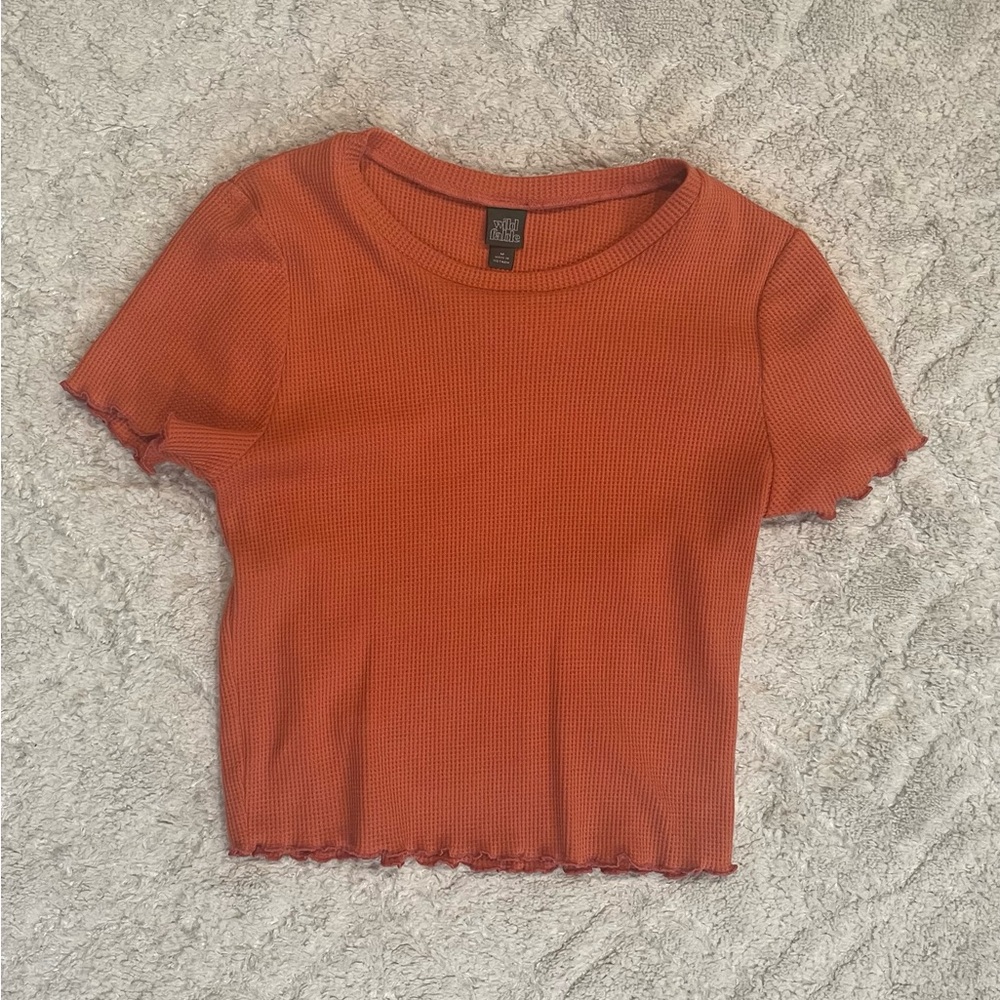 Burnt orange crop top. Ruffles on hem of arm and bottom of shirt.
